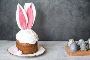 Beautiful stylish still life. Easter cake with rabbit ears, meringue, marshmallows, Easter eggs and willow twigs on a dark background. happy Easter 2024.