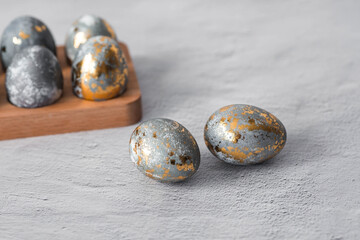 Stylish grey Easter eggs made of marble and concrete with a golden potala on a grey background. Coloring eggs with natural dye karkade tea. . The concept of a happy Easter.