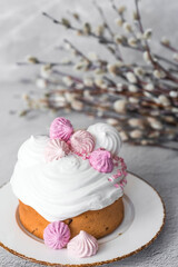 Beautiful stylish still life. Easter cake with meringue, marshmallows, Easter eggs and willow twigs on a light concrete background. happy Easter 2024.