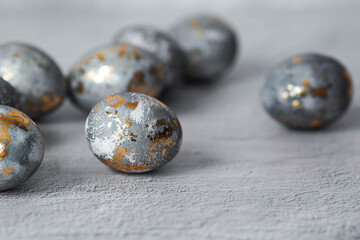 Stylish grey Easter eggs made of marble and concrete with a golden potala on a grey background. Coloring eggs with natural dye karkade tea. . The concept of a happy Easter.