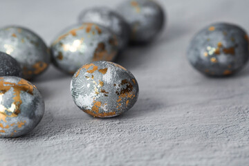Stylish grey Easter eggs made of marble and concrete with a golden potala on a grey background. Coloring eggs with natural dye karkade tea. . The concept of a happy Easter.