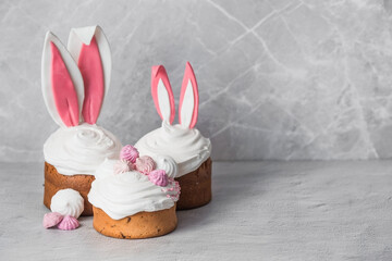 Fototapeta na wymiar Beautiful stylish still life. Easter cake with rabbit (hare) ears, meringue, marshmallows, Easter eggs and willow branches and on a light concrete background. Happy Easter 2024.