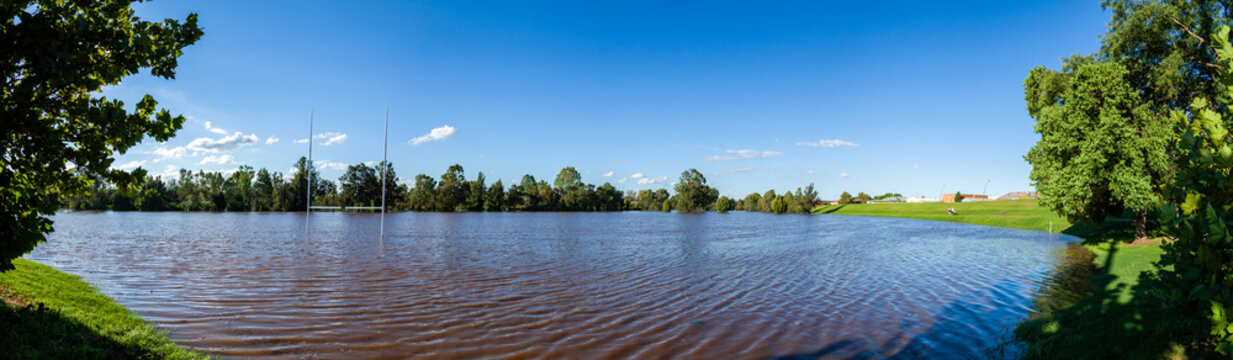 Brown floodwaters covering park playing field after river broke banks