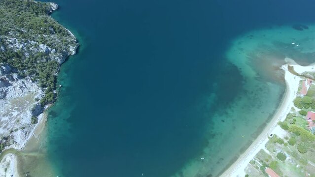 Cinematic slowly tilting up 4K drone clip over the tropical blue waters of Toroni in Chalkidiki