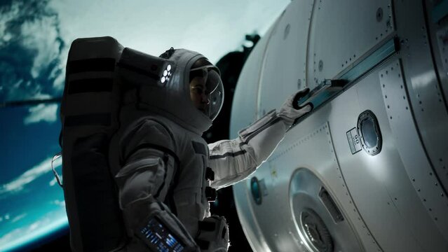 Space Engineer Servicing a Panel on a Communication Satellite with an Automatic Screw Gun. Brave Astronaut Working in Outer Space with Beautiful Blue Planet Earth in the Background