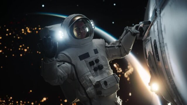 Portrait of a Young Male Astronaut Posing in a Space Suit During a Spacewalk Outside a Spaceship, Satellite or a Space Station. Spaceman Looking, Smiling and Waving Hello at Camera