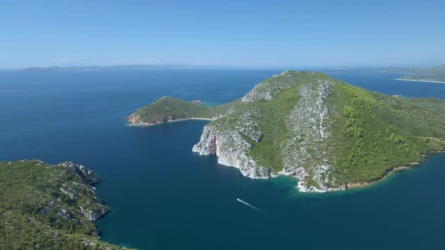 Cinematic rotating up high 4K drone clip over the tropical blue waters of Toroni in Chalkidiki with some boats passing by