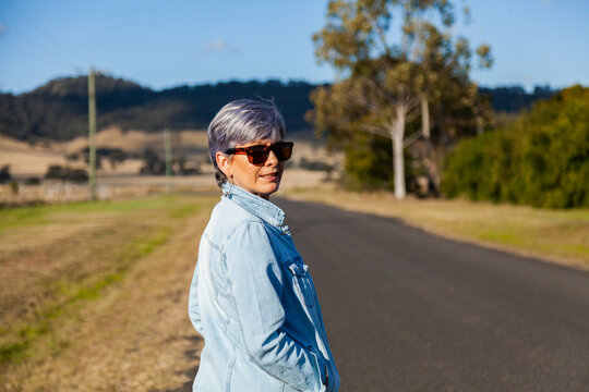Middle aged woman walking down a rural road for exercise