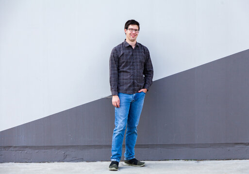 Person standing beside wall in urban area - full length body shot of young man