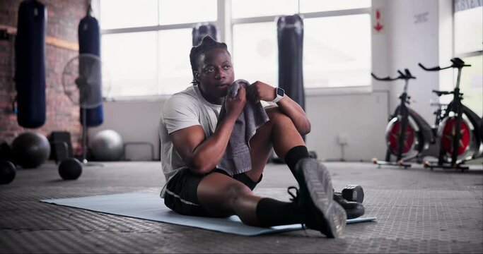 Fitness, tired and black man on floor with towel rest for bodybuilder training, exercise and gym workout. Sports, sweat and person with fatigue, relax and on break for wellness, health and recovery