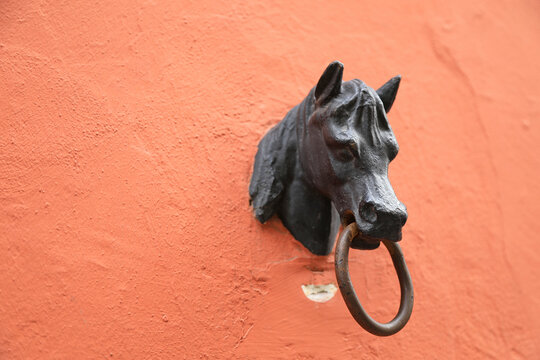 cabeza de caballo en hierro fundido con argolla para atar animales sobre la fachada de una casa color teja sevilla 4M0A5272-as24