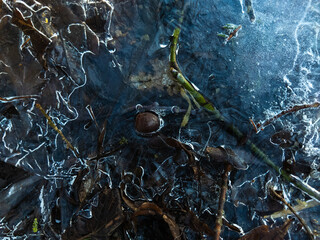 Cracked ice in a frozen puddle. Textures and patterns of the ice surface. Beautiful background image.