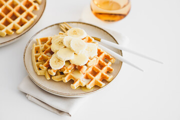 Belgian waffles with banana and condensed milk on white table. Top view