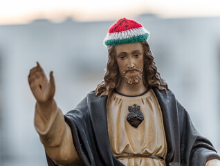 Statue of Jesus Christ wearing a knitted hat in the colors of The Palestinian flag