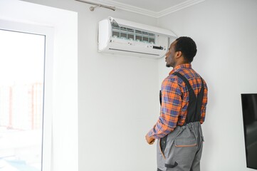 Fototapeta na wymiar Young African Male Technician Repairing Air Conditioner