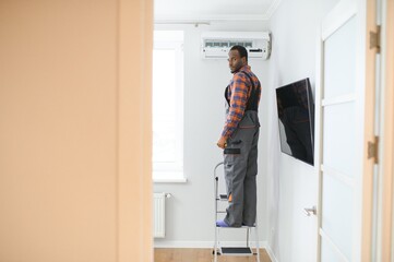 Fototapeta na wymiar African American electrician repairing air conditioner indoors