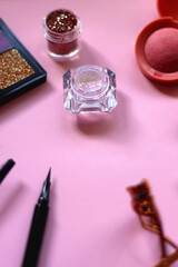 Various colorful make up products on pastel pink background. Selective focus.