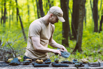 guy in the woods tests his weapons for shooting sports