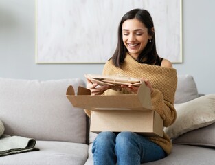 delivery, mail and people concept - smiling woman opening cardboard box at home.