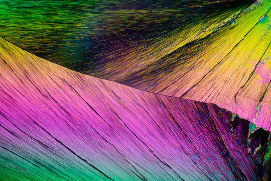 Vivid lines and waves of color flow through erythritol sugar crystals under polarized light microscopy