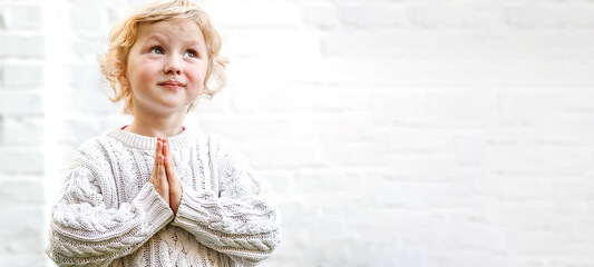 serene expression as the child clasps their hands in quiet prayer.