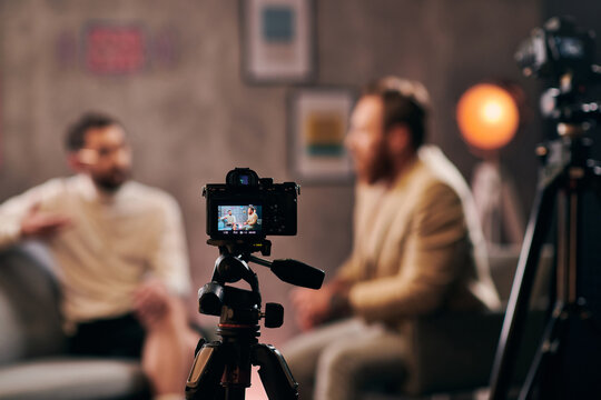 focus on camera filming stylish blurred men with beards in elegant attires discussing questions