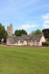 Pink painted thatched cottages, in front of St Mary's Church, Cavendish, Suffolk