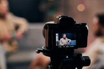 focus on camera filming stylish blurred man with beard in elegant attire discussing questions