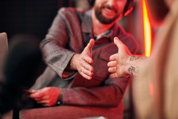 cropped view of men in everyday comfortable attires shaking hands during podcast while in studio