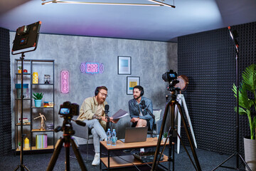 good looking stylish interviewer talking to his young guest with headphones during podcast