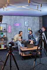 good looking stylish interviewer talking to his young guest with headphones during podcast