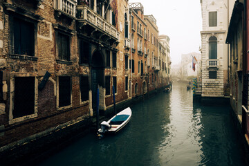 Small waterways of Venice. River canal with old brick medieval buildings in foggy day, Italy....