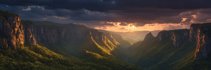 Obraz premium Majestic mountain landscape covered in lush green trees and surrounded by cloudy skies at sunset