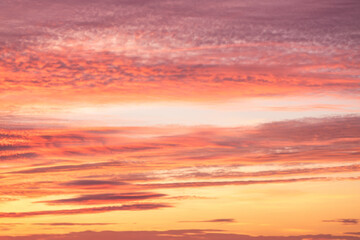 A beautiful sky tinted by the sun leaving vibrant shades of gold, pink, blue and multicolored. Clouds in the twilight evening and morning sky. Cloudy sky background in the evening and during the day.
