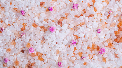 pink coarse salt with flower buds as a background, texture of coarse salt crystals, top view