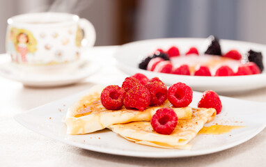 Breakfast of pancakes with fresh raspberries on table