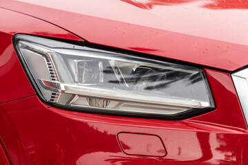Close up of the of  red  car with clear light headlight, bumper,  foglights