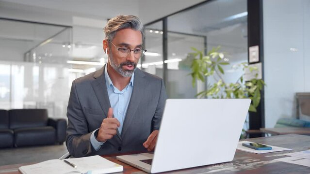 Middle-age Hispanic man using computer remote for business studying, watch online virtual webinar training meeting, video call. Smiling mature Indian or Latin businessman working on laptop in office.