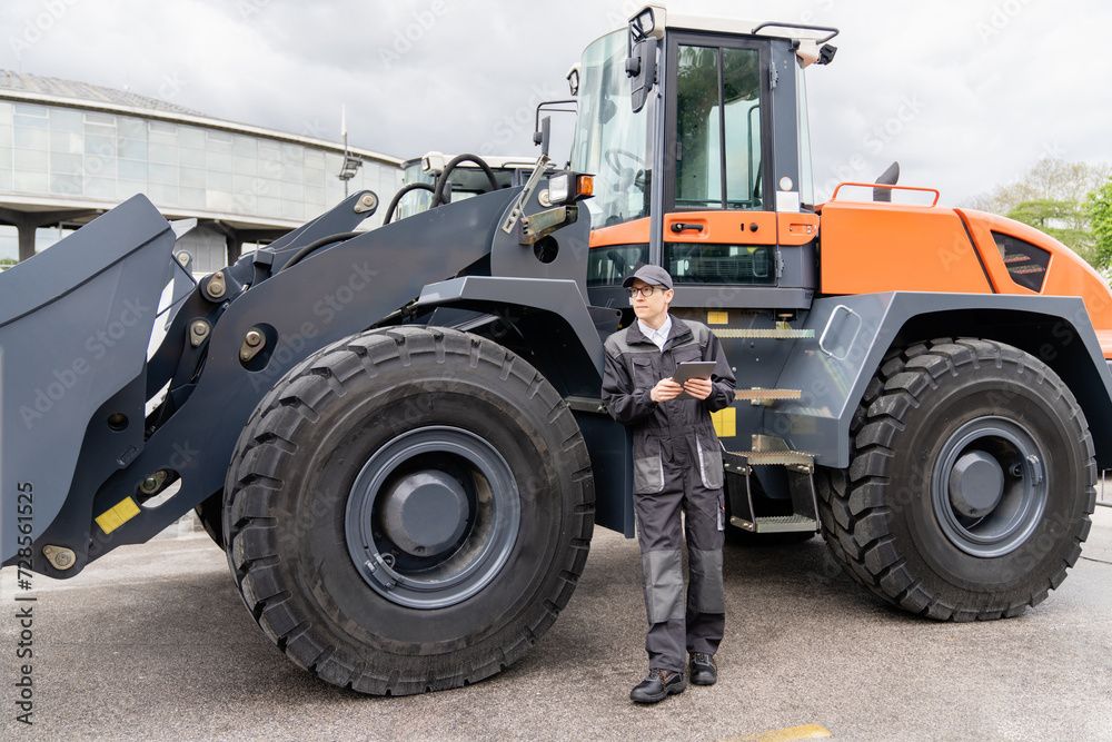 Poster serviceman with digital tablet on a background of the tractor.