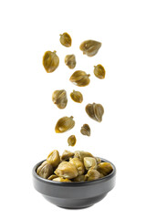 Pickled capers falling on a pile of capers close-up isolated on a white background.