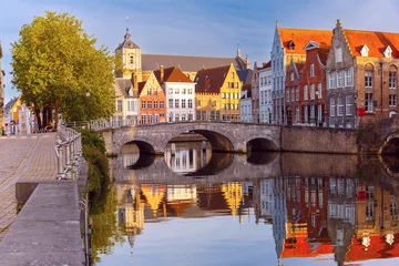 Poster Scenic city view of Bruges canal, medieval houses and sunny bridge at sunset, golden hour, Belgium © Kavalenkava