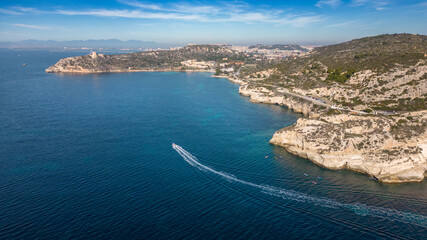 Aerial view with drone of the Sella del Diavolo in Cagliari. Sunny day, crystal clear sea with boats.