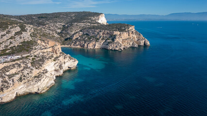 Fototapeta premium Aerial view with drone of the Sella del Diavolo in Cagliari. Sunny day, crystal clear sea with boats.