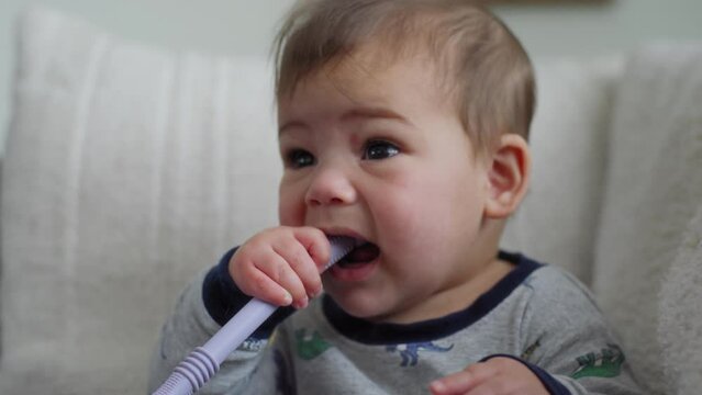 closeup shot of a baby boy chewing on a teething straw