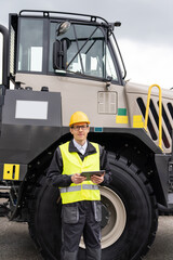 Engineer with tablet computer stands on the stairs to the cab of a truck.