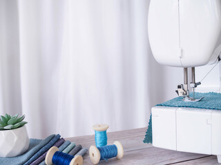 Close up sewing machine working with blue fabric, sewing accessories on the table, stitch new...