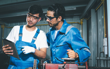 Two adult handsome male mechanics wearing uniform, using machine for fix, repair car or automobile components, teamwork helping, working in car maintenance service center or shop. Industry Concept.