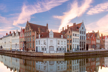 Scenic city view of Bruges canal, medieval houses and sunny bridge at sunset, golden hour, Belgium