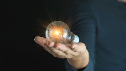 Businessman holding glowing lightbulb and human icon thinking with copy space for creative thinking idea and problem solving concept.