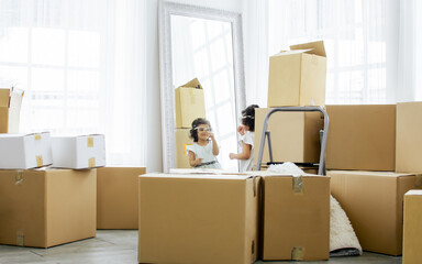 Selective focus on little caucasian cute sweet curly hair girl playing and standing with unpacking paper boxes for moving to new comfortable house or home or apartment with fun and happiness.